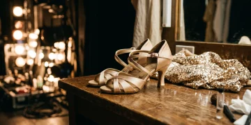Professional ballroom dance shoes and a sequined costume on a dressing table.
