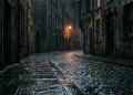 A moody, rainy street scene in a Northern Irish city at night.