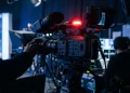 A professional broadcast camera in a darkened television studio.