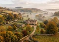 A conceptual view of an elegant manor house in the British countryside during autumn.