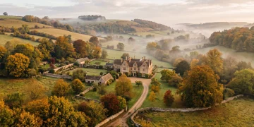 A conceptual view of an elegant manor house in the British countryside during autumn.