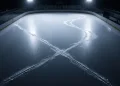 An overhead shot of intersecting ice skate trails on a skating rink.