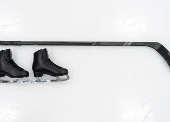 Figure skates and a hockey stick on ice representing the series .