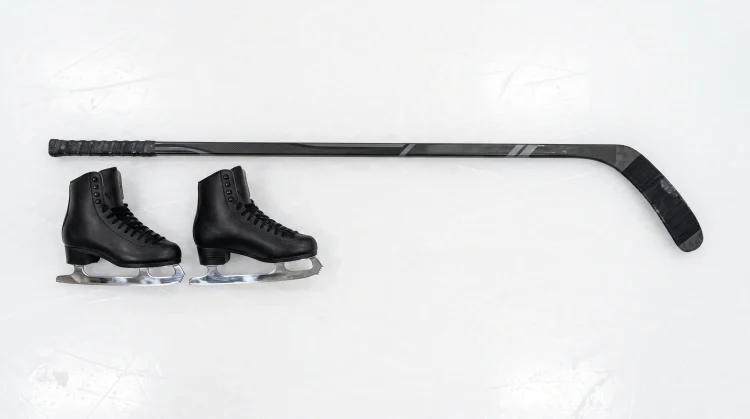 Figure skates and a hockey stick on ice representing the series .