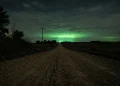 A rural Nebraska road at night glowing with a mysterious green light from the horizon.