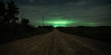 A rural Nebraska road at night glowing with a mysterious green light from the horizon.