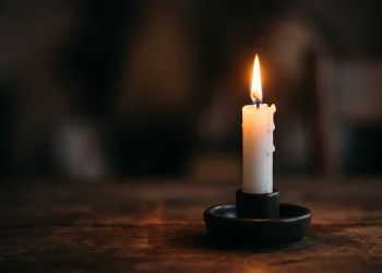 A soft glowing candle in a darkened room representing remembrance.