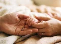 Conceptual image of parents holding a newborn's hand.