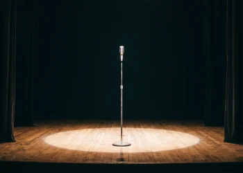 A microphone stand centered in a stage spotlight