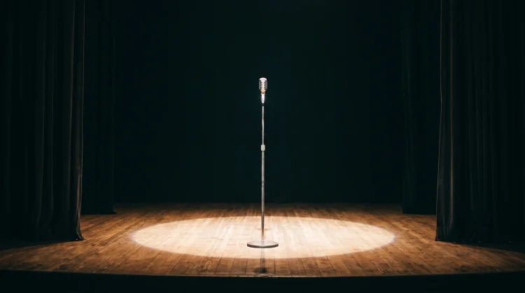 A microphone stand centered in a stage spotlight
