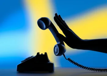 A hand pushing away a telephone receiver to symbolize ending a call abruptly.