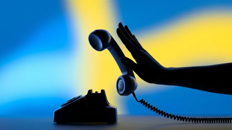 A hand pushing away a telephone receiver to symbolize ending a call abruptly.