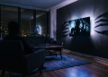 A dark living room with eerie blue and purple light reflecting from a television screen.