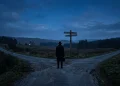A conceptual cinematic image of a figure at a crossroads under blue lighting.