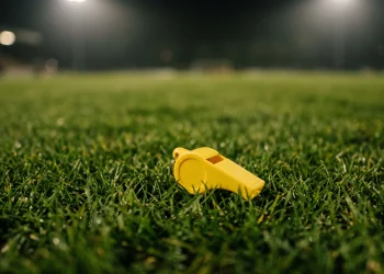 A close-up of a coach's whistle on a football pitch.