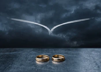 A conceptual image of a plane trail splitting and two wedding rings representing a double life.